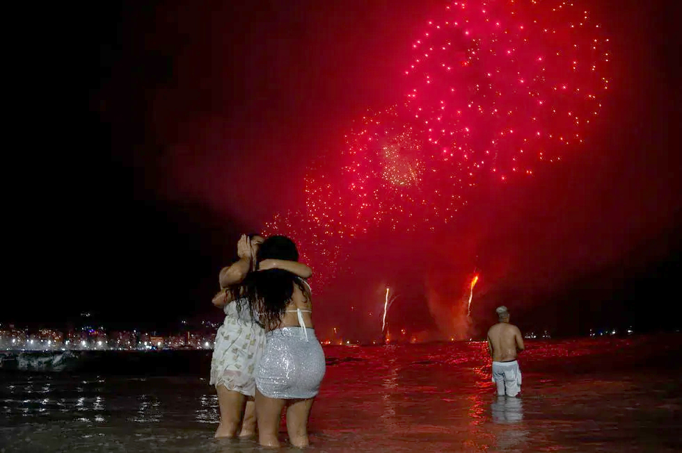 La gente celebra mientras observa los tradicionales fuegos artificiales de Año Nuevo desde el agua en la playa de Copacabana en Río de Janeiro, Brasil, el 1 de enero de 2024. (Foto de TERCIO TEIXEIRA / AFP). / TERCIO TEIXEIRA