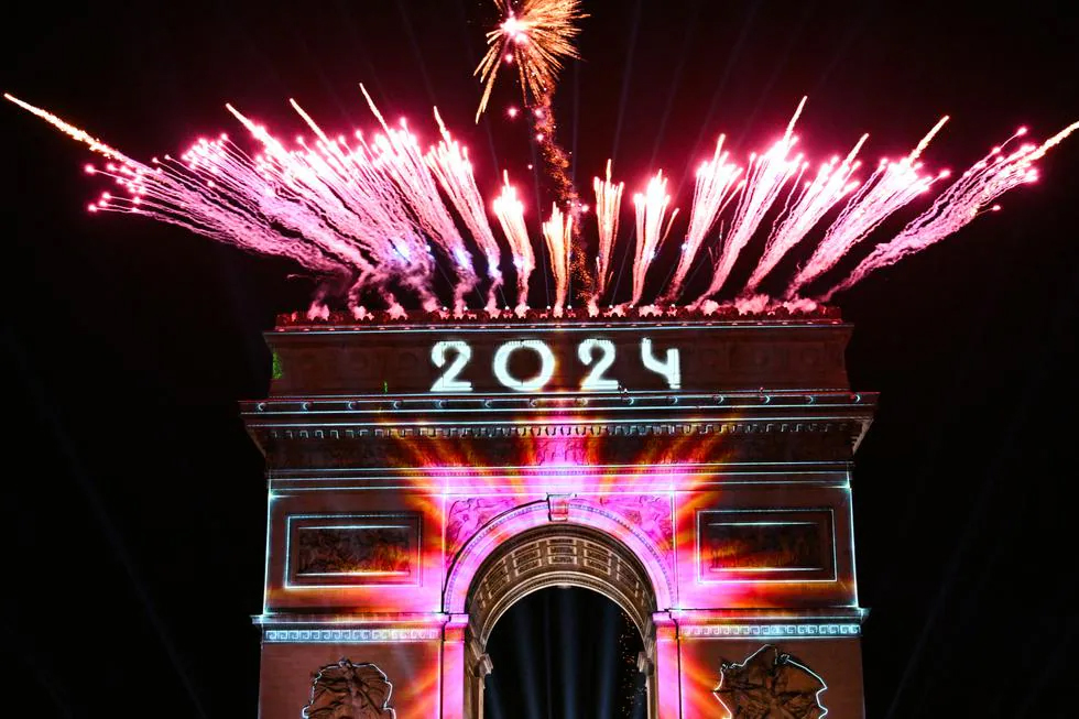 Los fuegos artificiales explotan junto al Arco de Triunfo con la palabra "2024" proyectada, en la Avenida de los Campos Elíseos, durante las celebraciones del Año Nuevo en París, Francia, a primera hora del 1 de enero de 2024. (Foto de Bertrand GUAY / AFP). / BERTRAND GUAY